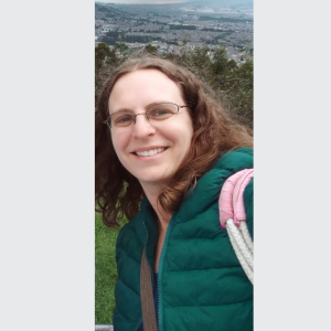 A woman in a green jacket smiling. 